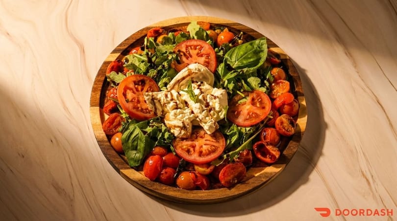 Caprese salad with fresh mozzarella, sliced tomatoes, cherry tomatoes, basil, and balsamic glaze.